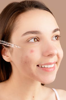 Smiling young woman applying acne treatment serum on face